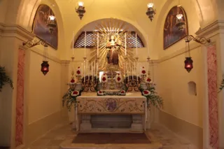 Interno della chiesa di San Nicolino con altare in marmo, statua di San Nicola Pellegrino in una nicchia raggiata, lampade votive e fiori
