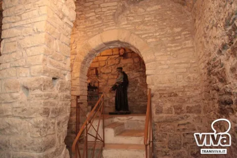 Statua di un frate in una nicchia ad arco, in cima a una breve scala, nei sotterranei