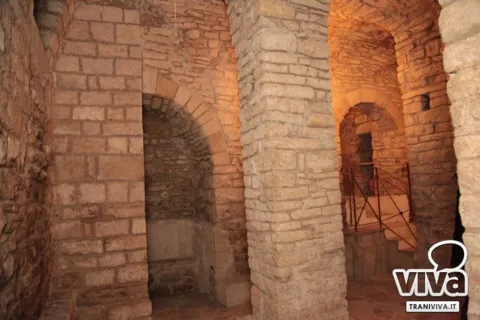 Pilastri, archi in pietra e una scala in muratura con ringhiera nei sotterranei