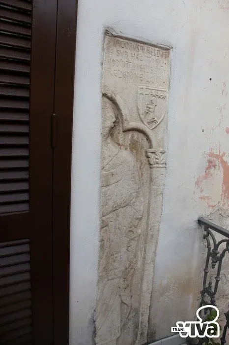 Metà della lastra di sarcofago, con iscrizione e stemma, murata accanto alla porta del balcone