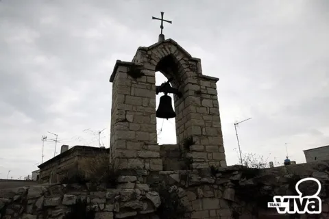 Campaniletto a vela con la campana e la croce, sul tetto della chiesa
