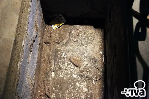 Bassorilievo consunto di una figura distesa, in una fossa di pietra