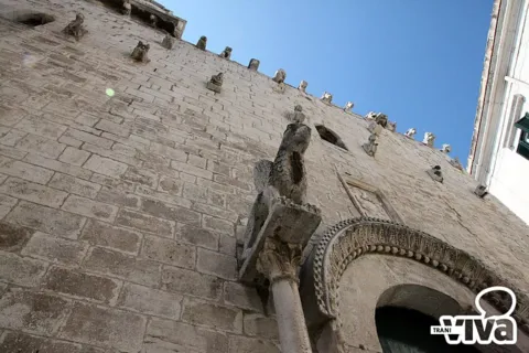 La facciata di scorcio: la colonnina con il grifo, l'arco del portale e le sculture in alto
