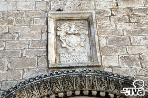 La lapide del 1647 con stemma e iscrizione latina, sopra l'arco scolpito del portale