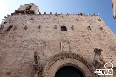 La facciata di San Giacomo vista dal basso, con il portale, la lapide e le file di sculture