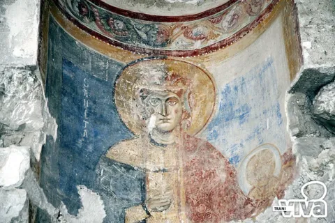 Affresco di una santa con aureola che regge un tondo con il volto di Cristo