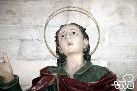 Volto di una statua dei Misteri: un giovane santo con aureola, veste verde e manto rosso