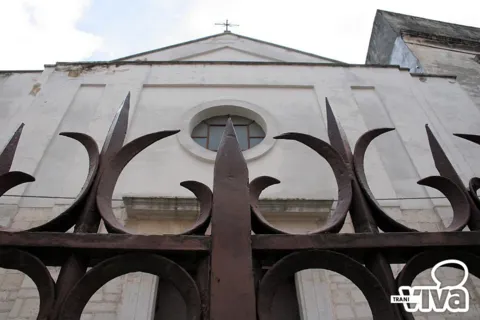 La facciata di San Toma vista dal basso attraverso le punte della cancellata in ferro