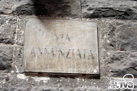 Targa in pietra con l’iscrizione «Via Annunziata», murata in una parete di conci scuri