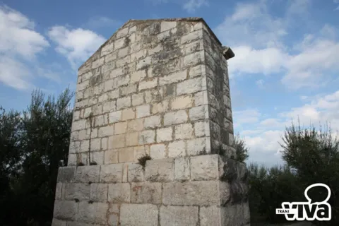 Un lato del monumento senza lapidi, in blocchi di pietra chiara, contro il cielo azzurro