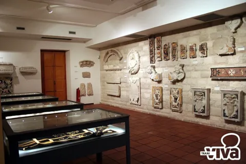 Sala con rilievi, frammenti in pietra e stemmi scolpiti alle pareti e vetrine basse al centro