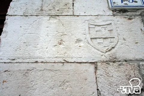 Scudo a scacchi appena inciso su un blocco di pietra della facciata, accanto al numero civico