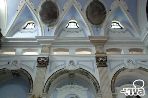Parete della navata con arcate, capitelli scolpiti e medaglioni dipinti nelle lunette, in azzurro e bianco