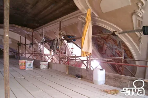 Impalcatura sotto la volta durante i lavori, con secchi e attrezzi accanto a un affresco ovale
