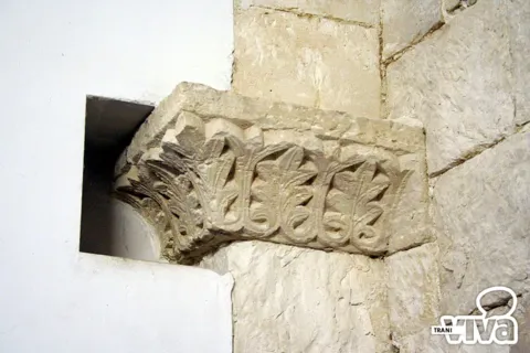 Frammento di capitello a foglie d'acanto che sporge dalla parete accanto a una nicchia
