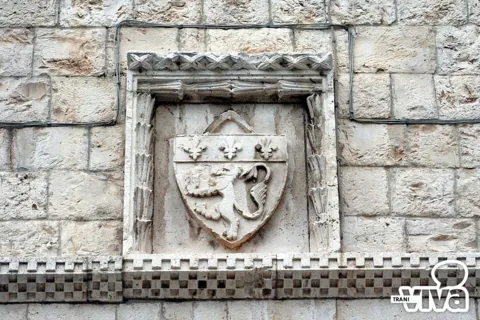 Stemma con leone rampante e tre gigli in una cornice scolpita, sopra una fascia a scacchi