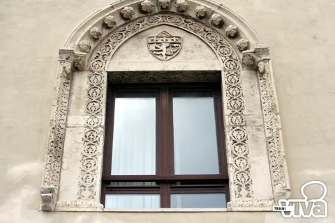 Finestra con cornice scolpita a rosette e intrecci e lo stemma del leone nella lunetta