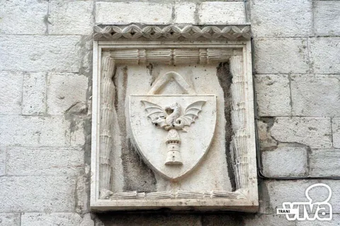 Stemma in pietra con una torre sormontata da un drago alato, in una cornice scolpita