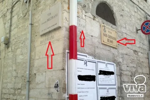 Angolo di palazzo Morola: targhe di stili diversi per via Beltrani e via San Giovanni Russo, segnate da frecce rosse