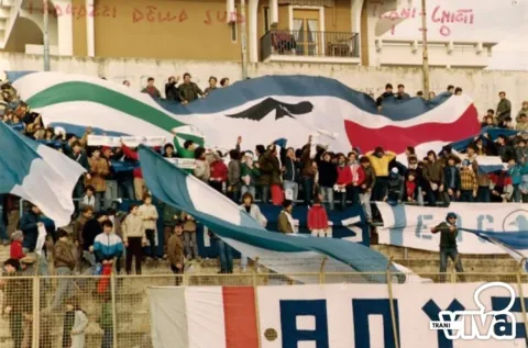 Tifosi in curva con grandi bandiere, una con un'aquila, e striscioni sugli spalti dello stadio