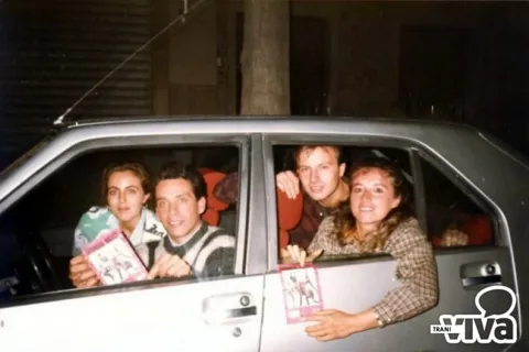Quattro ragazzi affacciati ai finestrini di un'auto mostrano dei cartoncini illustrati
