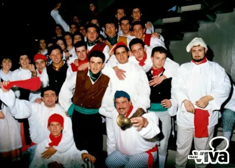 Giovani in costume, con camicie bianche, berretti e fazzoletti rossi, in posa su una scalinata