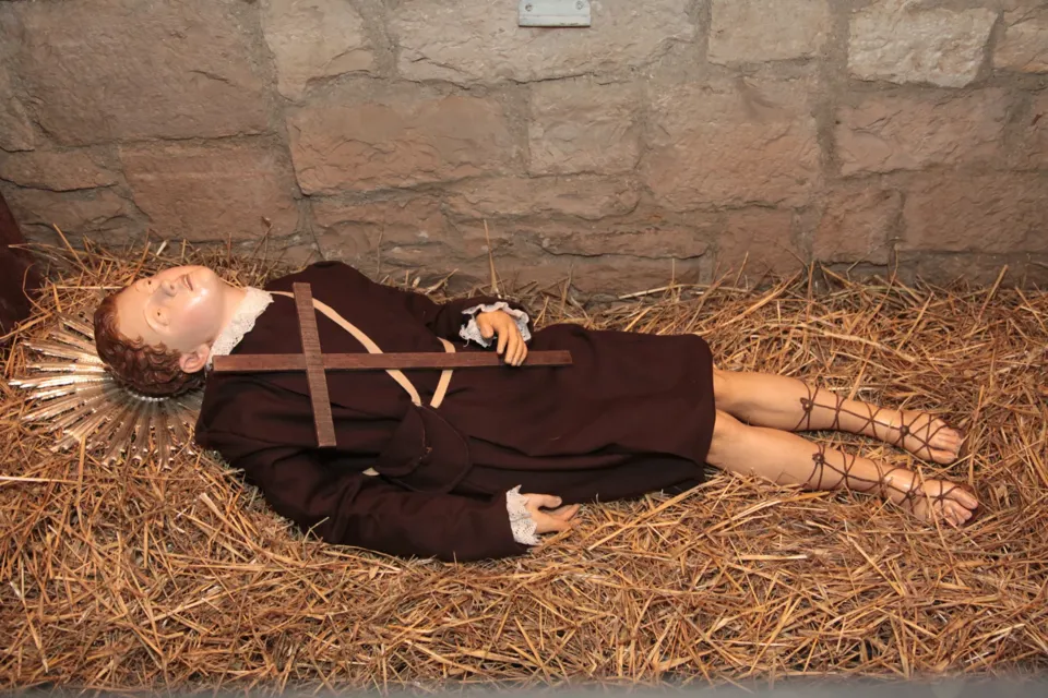 Statua di santo giacente su paglia