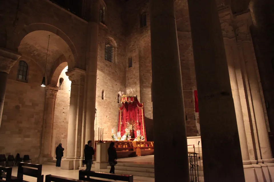 Interno della Cattedrale in penombra con alte colonne e archi; sul fondo l'altare della reposizione con drappi rossi e alcuni fedeli