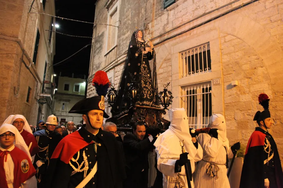 La statua dell'Addolorata avanza tra le case in pietra scortata da Carabinieri in alta uniforme con pennacchio e da confratelli