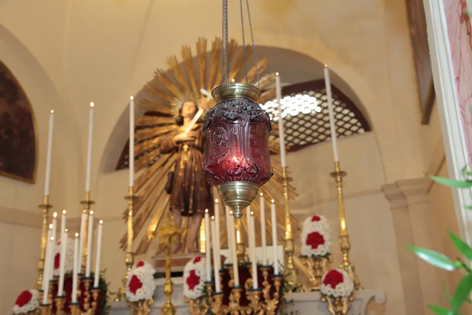 Altare della chiesa di San Nicolino con candelieri, fiori rossi e bianchi, una lampada votiva rossa e la statua di San Nicola Pellegrino in una raggiera dorata
