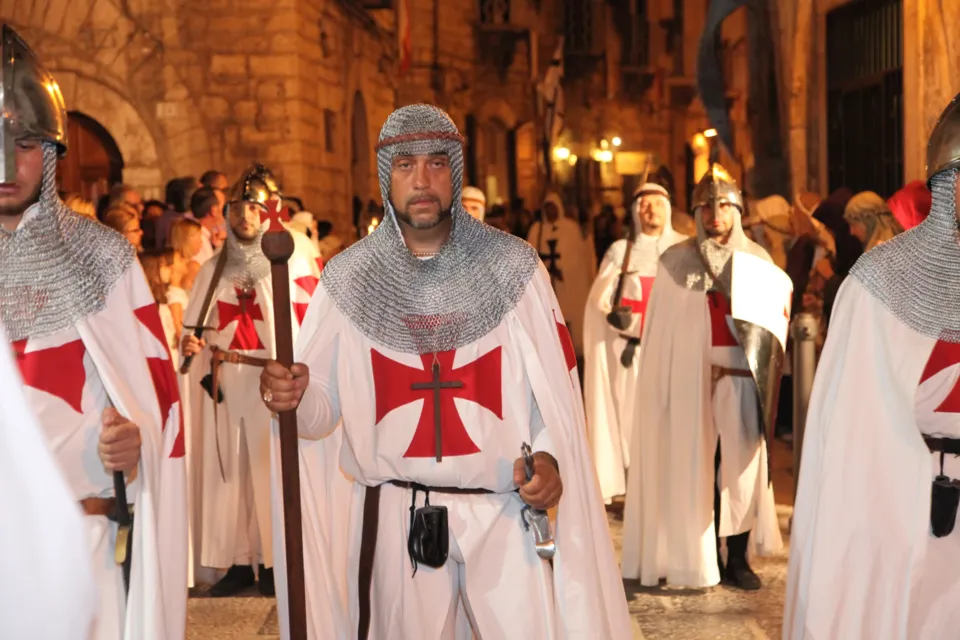 Figuranti vestiti da cavalieri templari, con cotta di maglia e tunica bianca con croce rossa, sfilano di notte