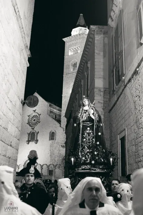 La statua dell'Addolorata con i confratelli in primo piano e il campanile della Cattedrale illuminato sullo sfondo