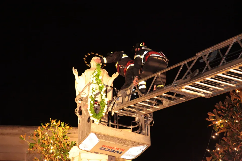 Dal cestello dell'autoscala i vigili del fuoco pongono la corona di fiori sulla statua dell'Immacolata in cima alla colonna