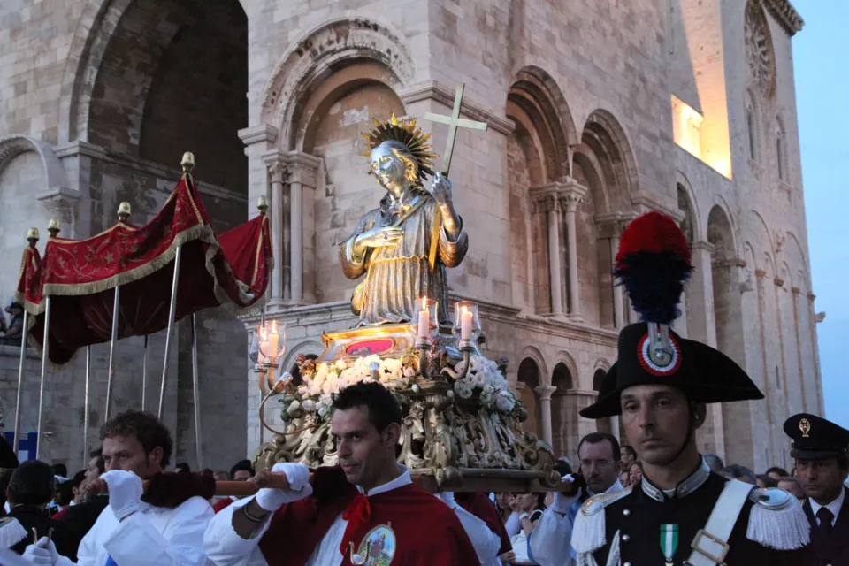 La statua di San Nicola Pellegrino in processione davanti alle arcate della facciata della Cattedrale, scortata da carabinieri in alta uniforme, con il baldacchino rosso