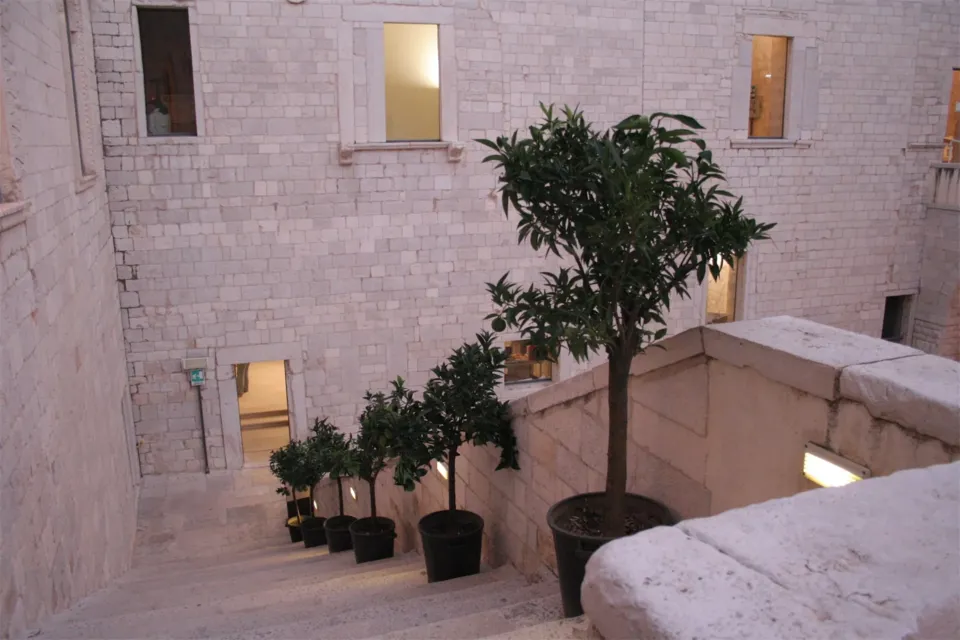 Rampa e terrazzino interni al Castello Svevo con piccoli alberi di agrumi in vaso, tra pareti in pietra con finestre