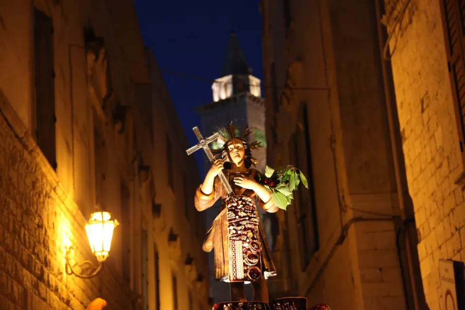Statua di San Nicola Pellegrino portata di sera in una stretta via del centro storico, con il campanile della Cattedrale illuminato sullo sfondo