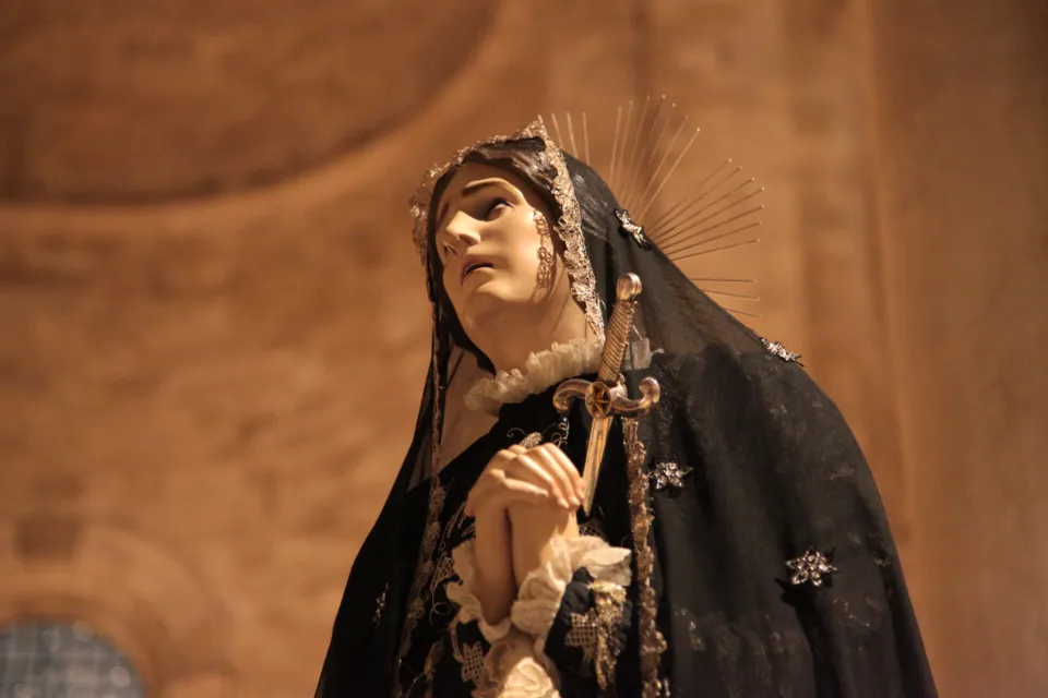 Dettaglio della statua dell'Addolorata con manto nero ricamato, aureola a raggiera e mani giunte, in processione