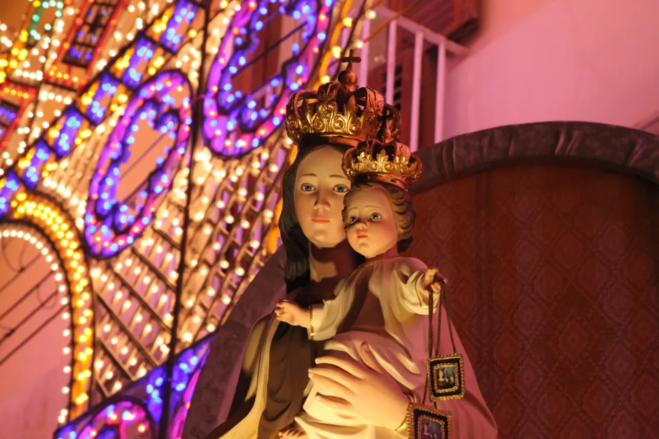 Statua della Madonna del Carmine con il Bambino, entrambi coronati, davanti alle luminarie