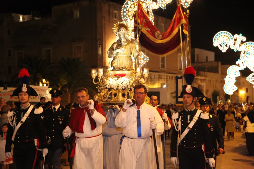 La statua argentea di San Nicola Pellegrino portata a spalla di notte tra le luminarie, preceduta da portatori in tunica bianca e scortata da carabinieri in alta uniforme