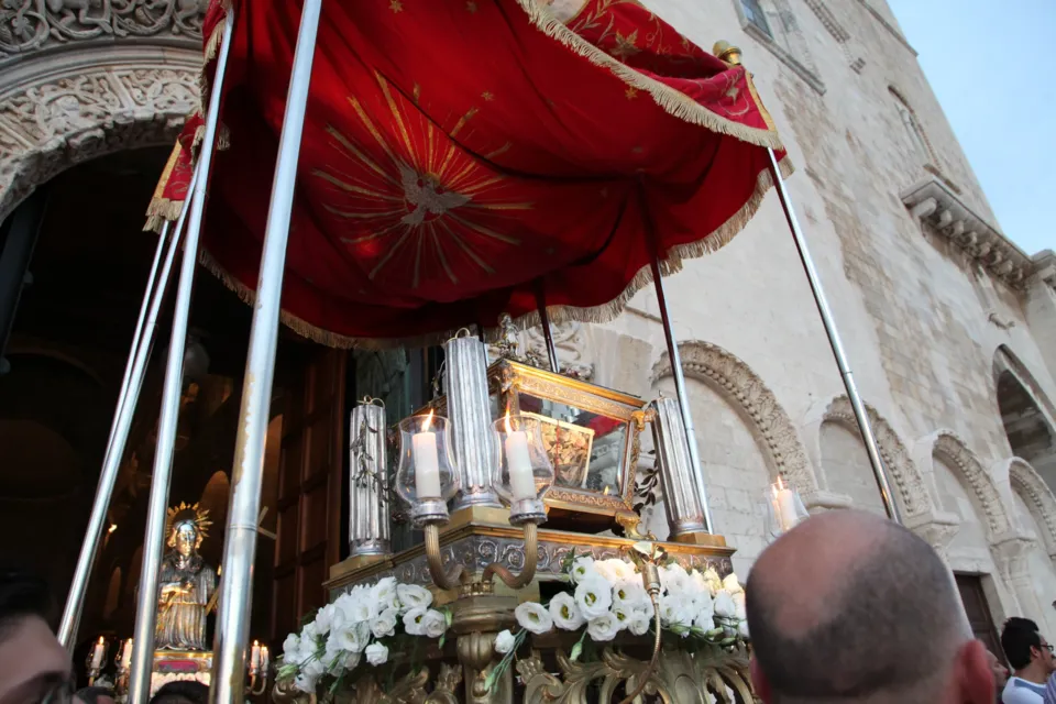 La statua argentea di San Nicola Pellegrino, su base fiorita e sotto un baldacchino rosso, esce dal portale della Cattedrale