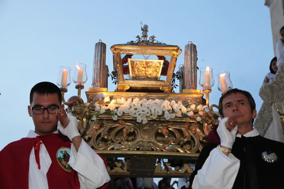 L'urna argentea con le reliquie di San Nicola Pellegrino, ornata di fiori bianchi e candele, portata a spalla dai confratelli nel cielo della sera